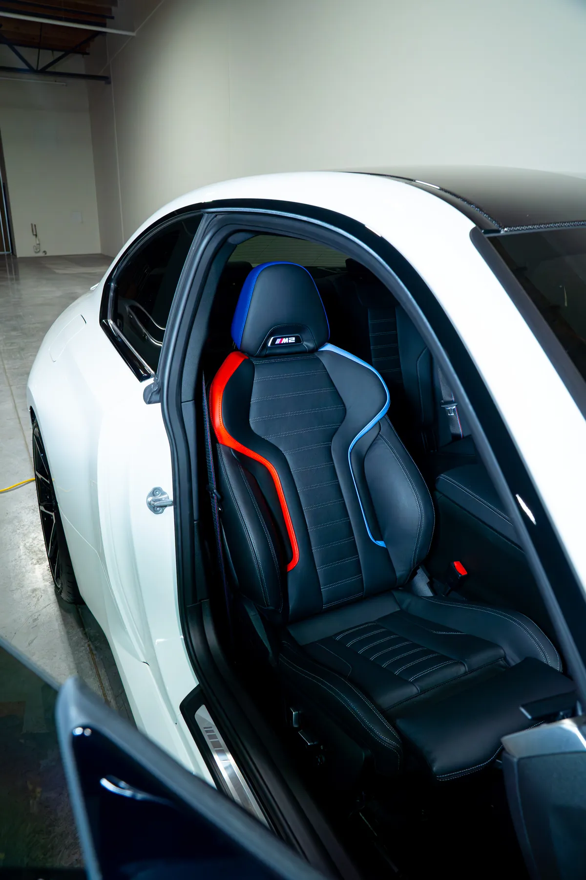 The cabin of a white BMW M2 with the door open after an interior detail