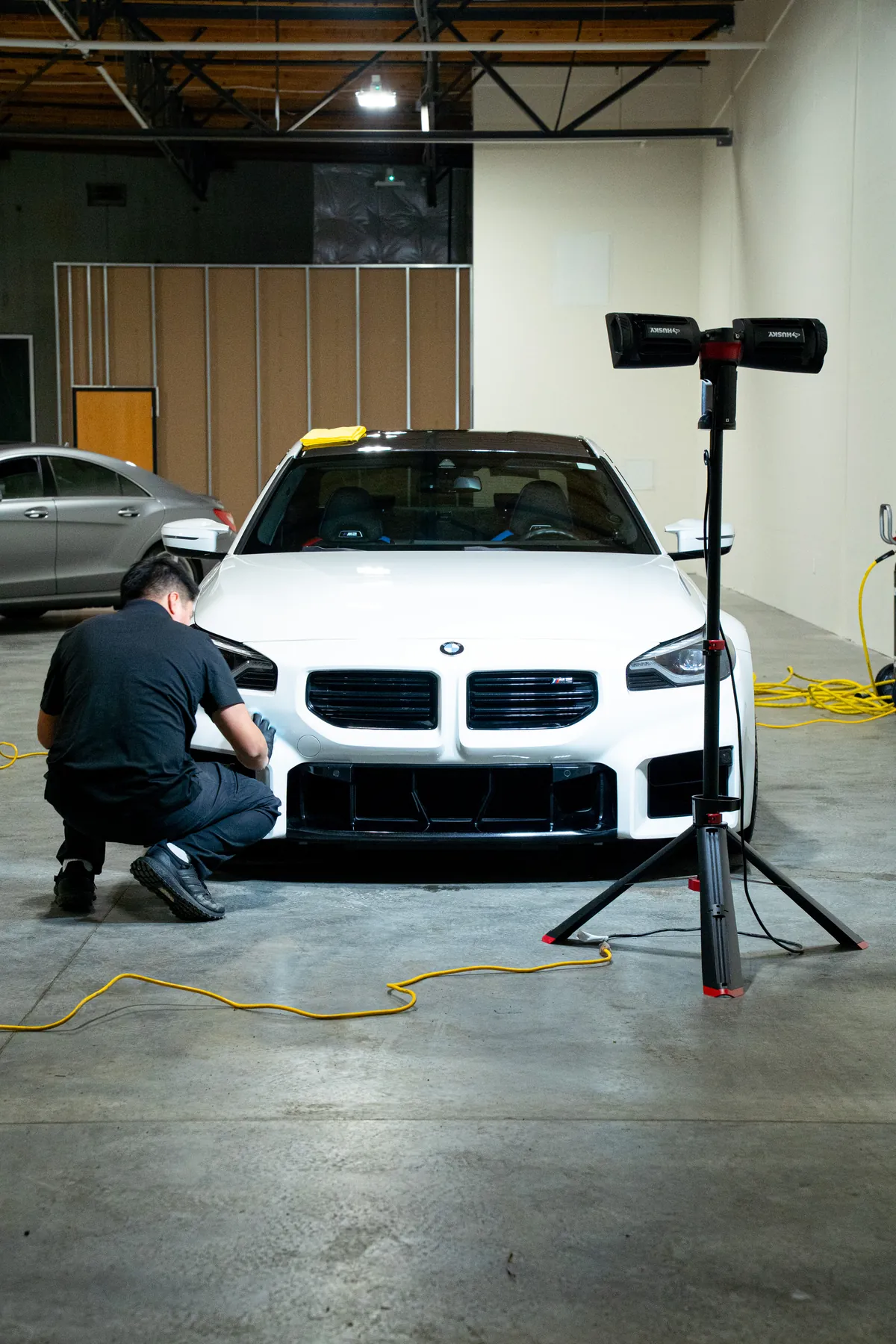 A white BMW M2 parked under an inspection light inside the studio