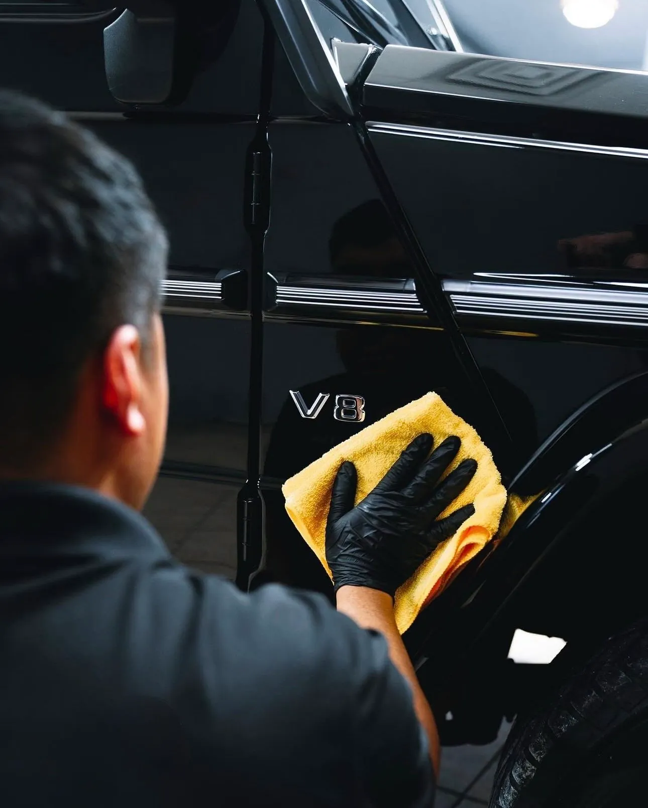 A technician hand finishing the black paintwork on a car door