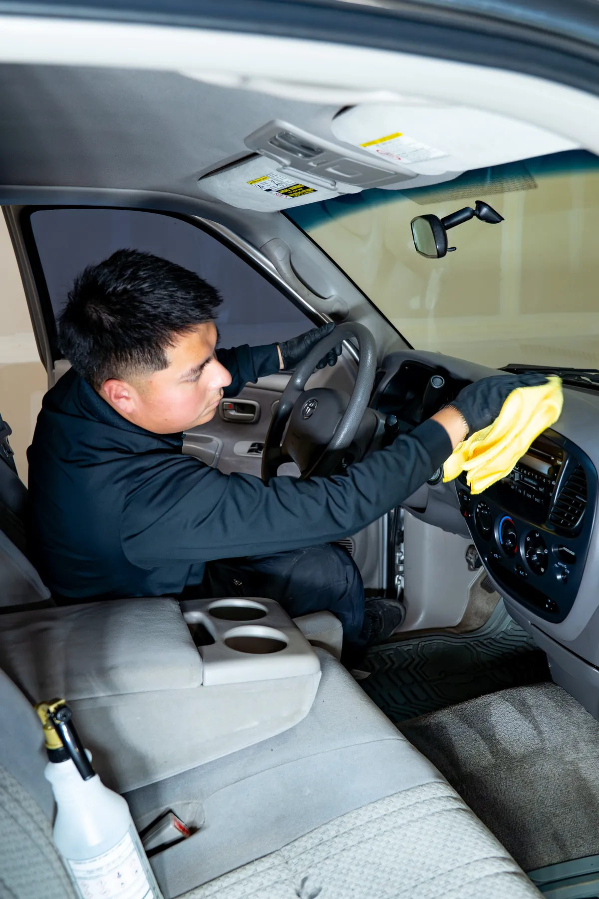 A technician cleaning the cloth seats and console of a daily driver
