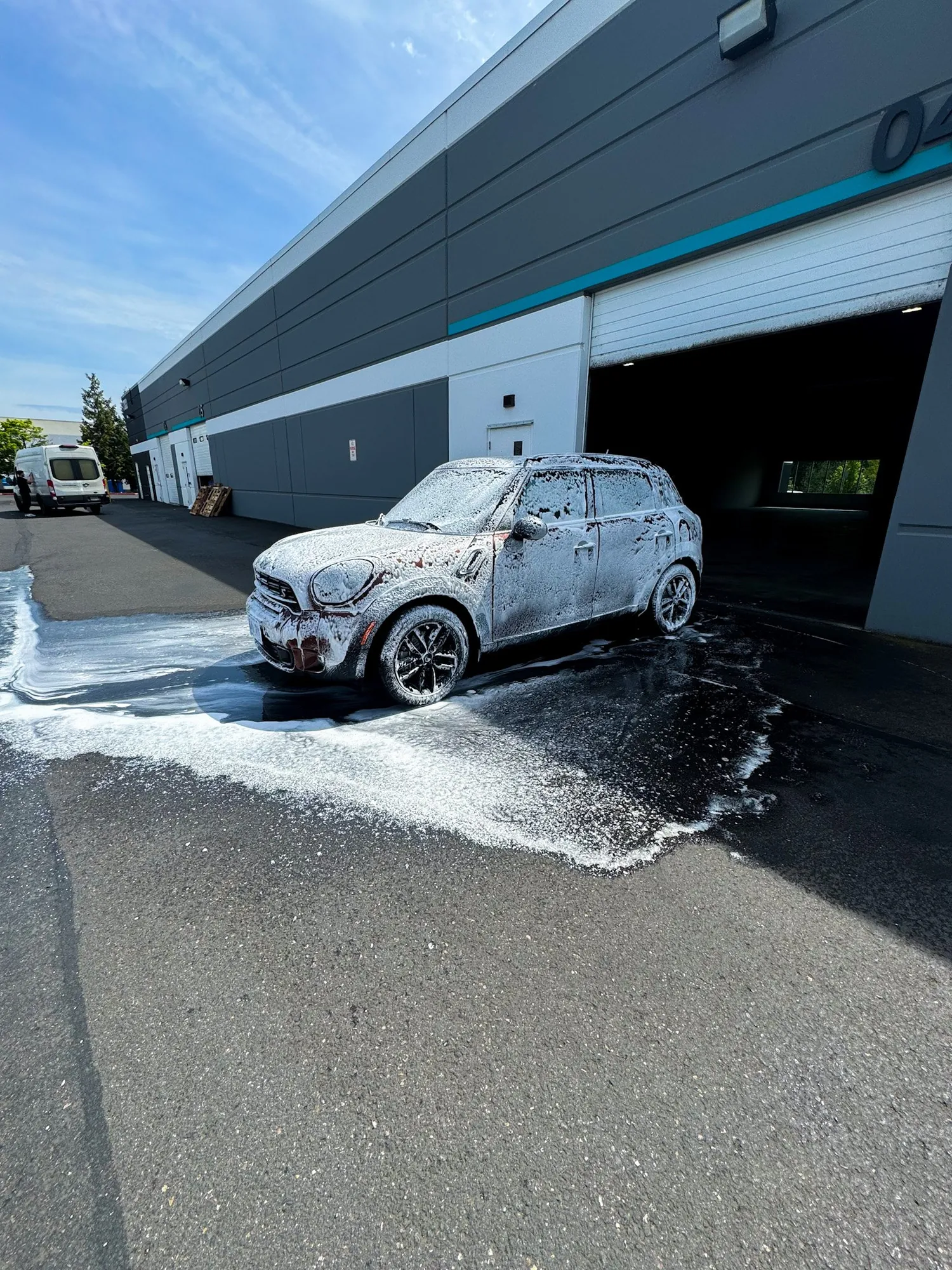 A Mini Cooper covered in hydro foam during a maintenance wash