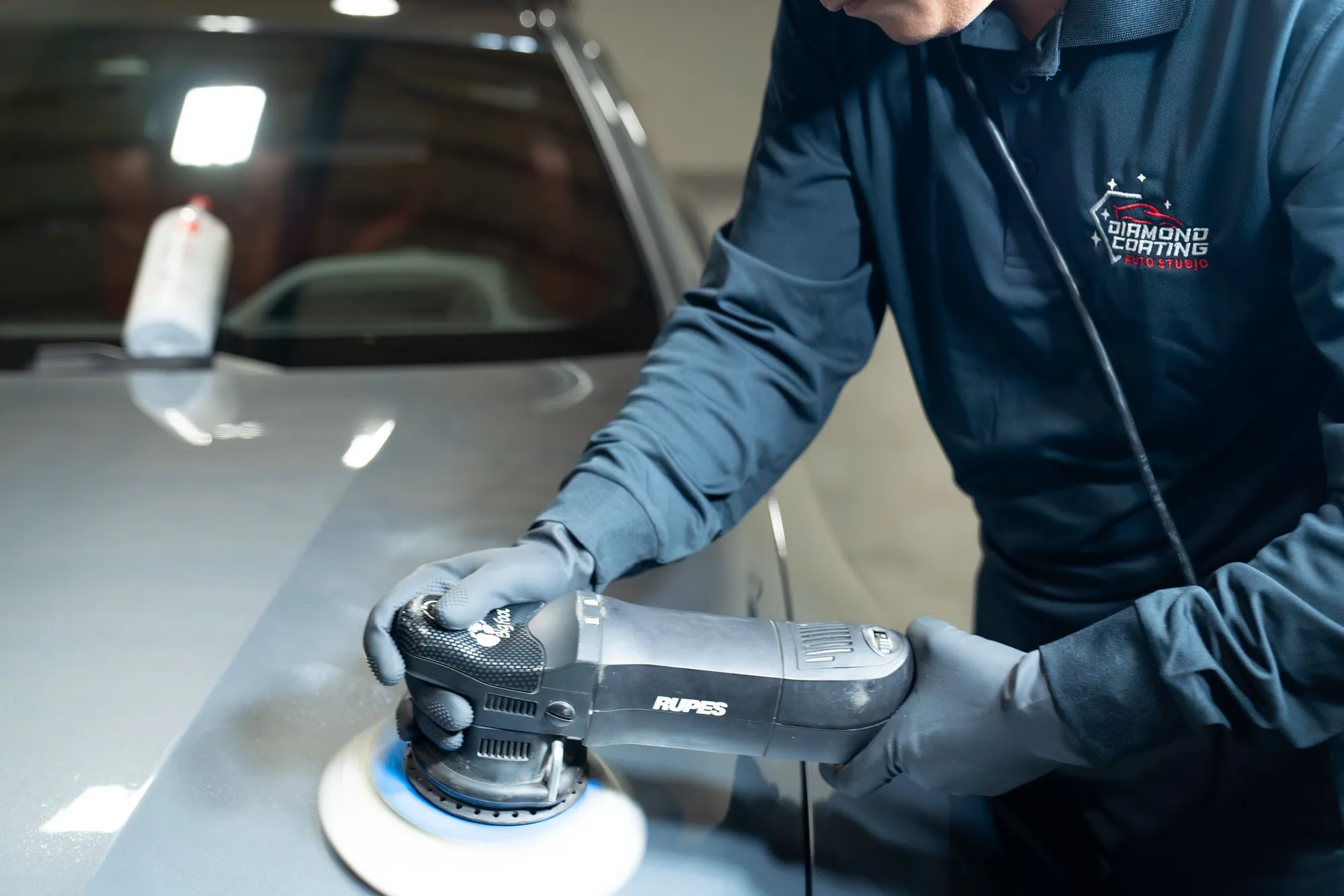 A technician machine polishing a car panel under the studio lights