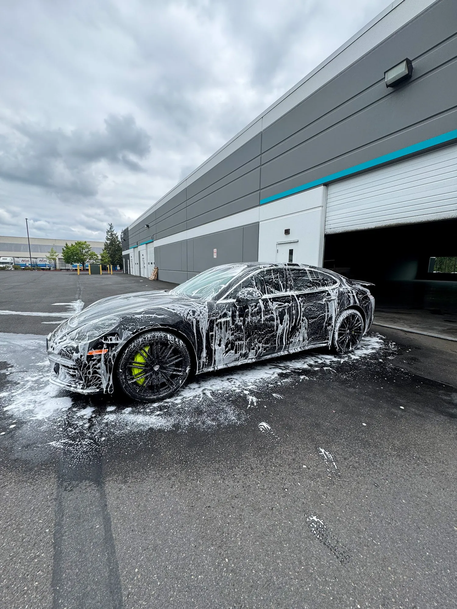A black Porsche Panamera covered in hydro foam outside the studio