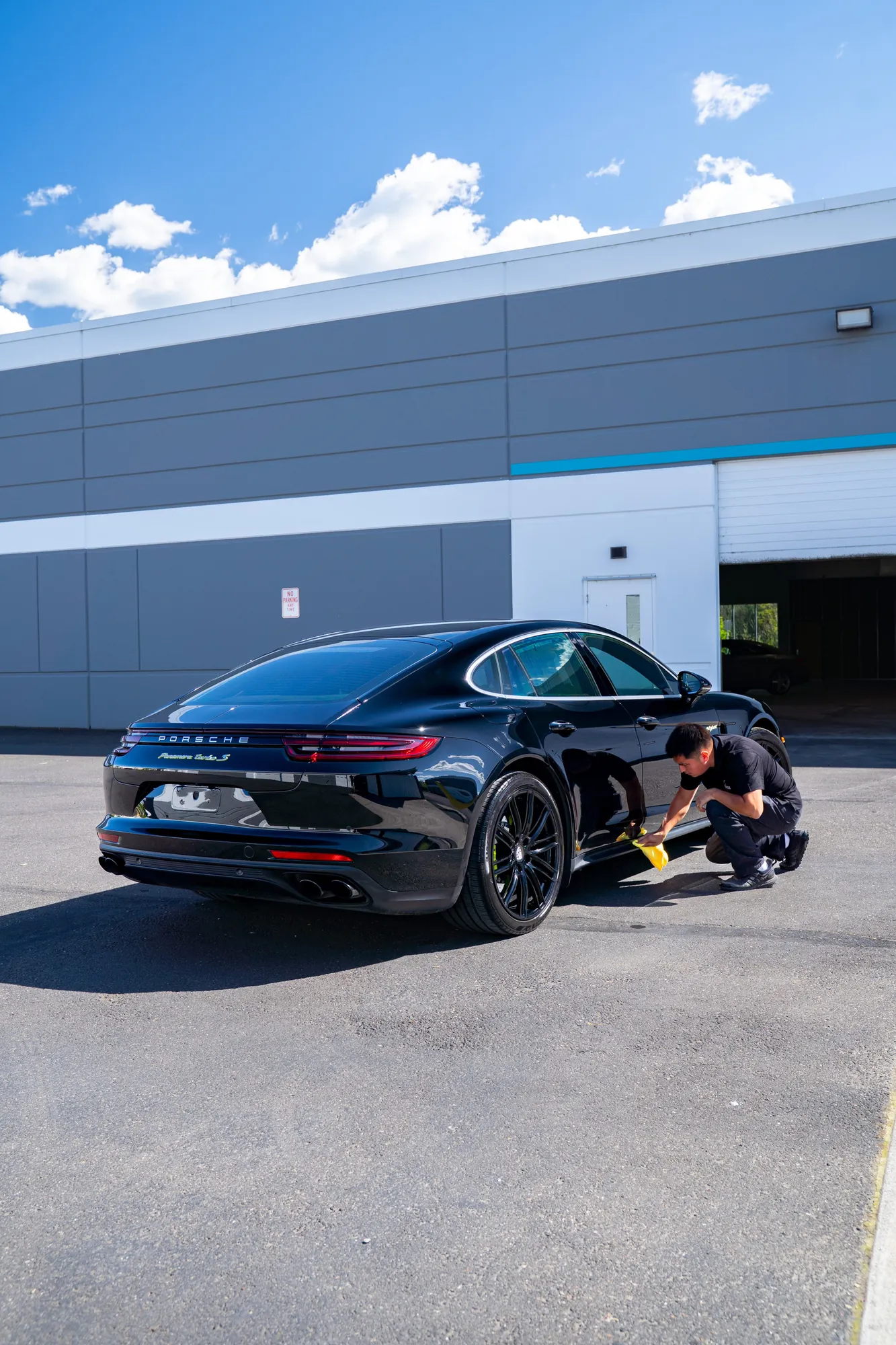 A technician working on a black Porsche Panamera outside the studio unit in Portland