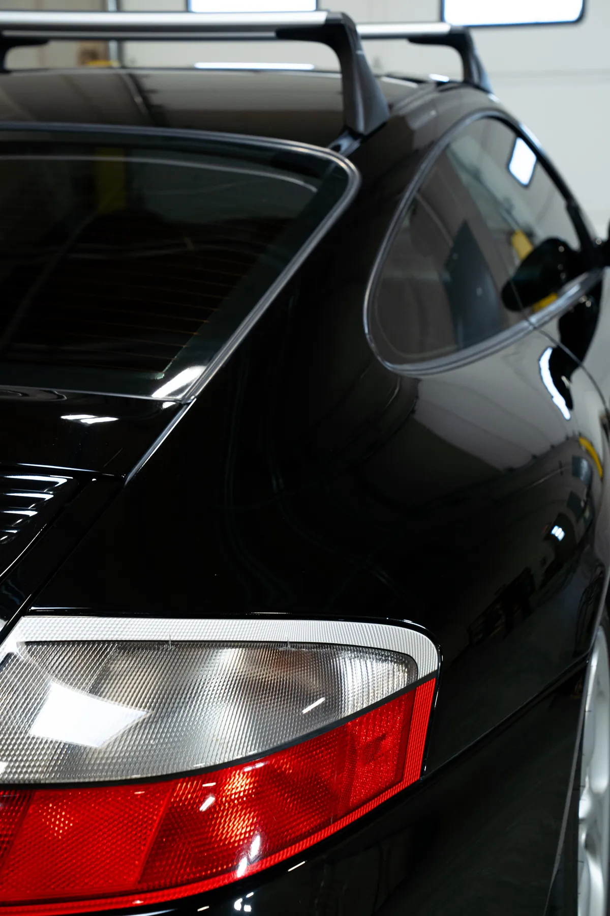 The polished rear quarter and taillight of a black Porsche 911